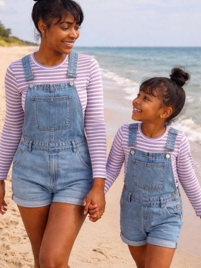 Mother and daughter holding hands, smiling at each other on the beach.