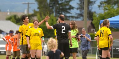 Soccer players celebrating with high fives and smiles on the field.