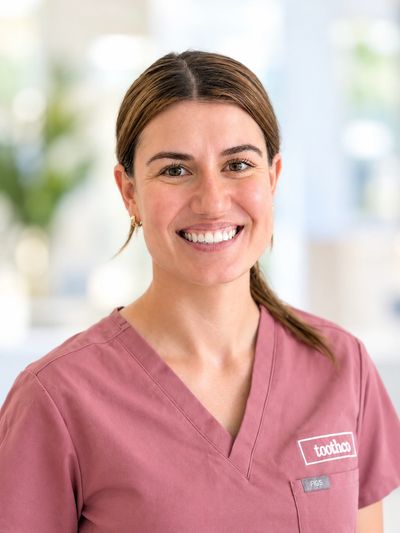Smiling woman in pink medical scrubs.