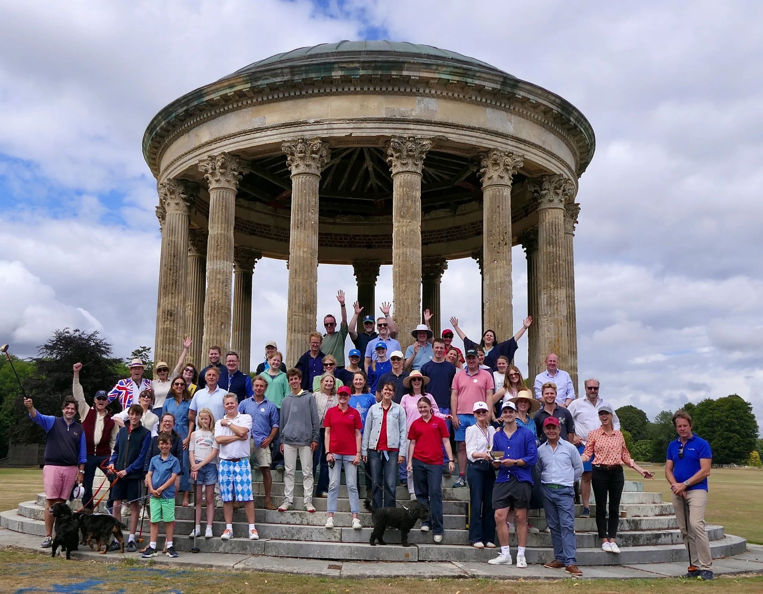 Large group of people posing in front of a classical round temple with columns.