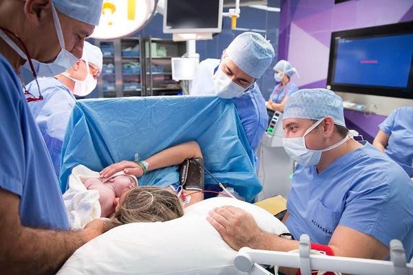 Medical team assists mother during childbirth in a hospital delivery room.