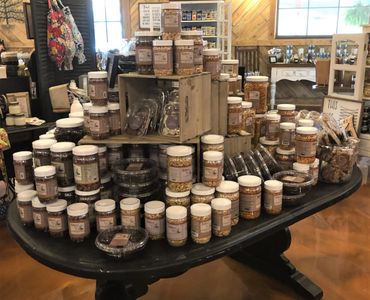 Table display of various jars and containers with food items in a cozy store setting.