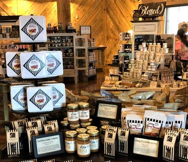 A display of various gourmet food products in a warm, rustic store setting.