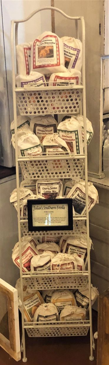 A vertical rack filled with various labeled fabric bags of baking mixes.
