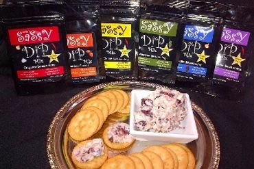 Assorted Sassy Dip Mix packets with crackers and dip on a silver tray.