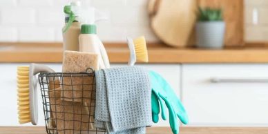 Cleaning supplies including brushes, gloves, and cloths in a kitchen basket.