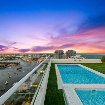 Rooftop pool with city and ocean view at sunset.