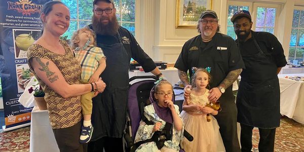 A family and chefs pose happily in a restaurant or event setting.