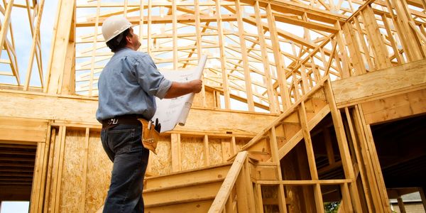 Construction worker inspecting wooden framework of a new building.