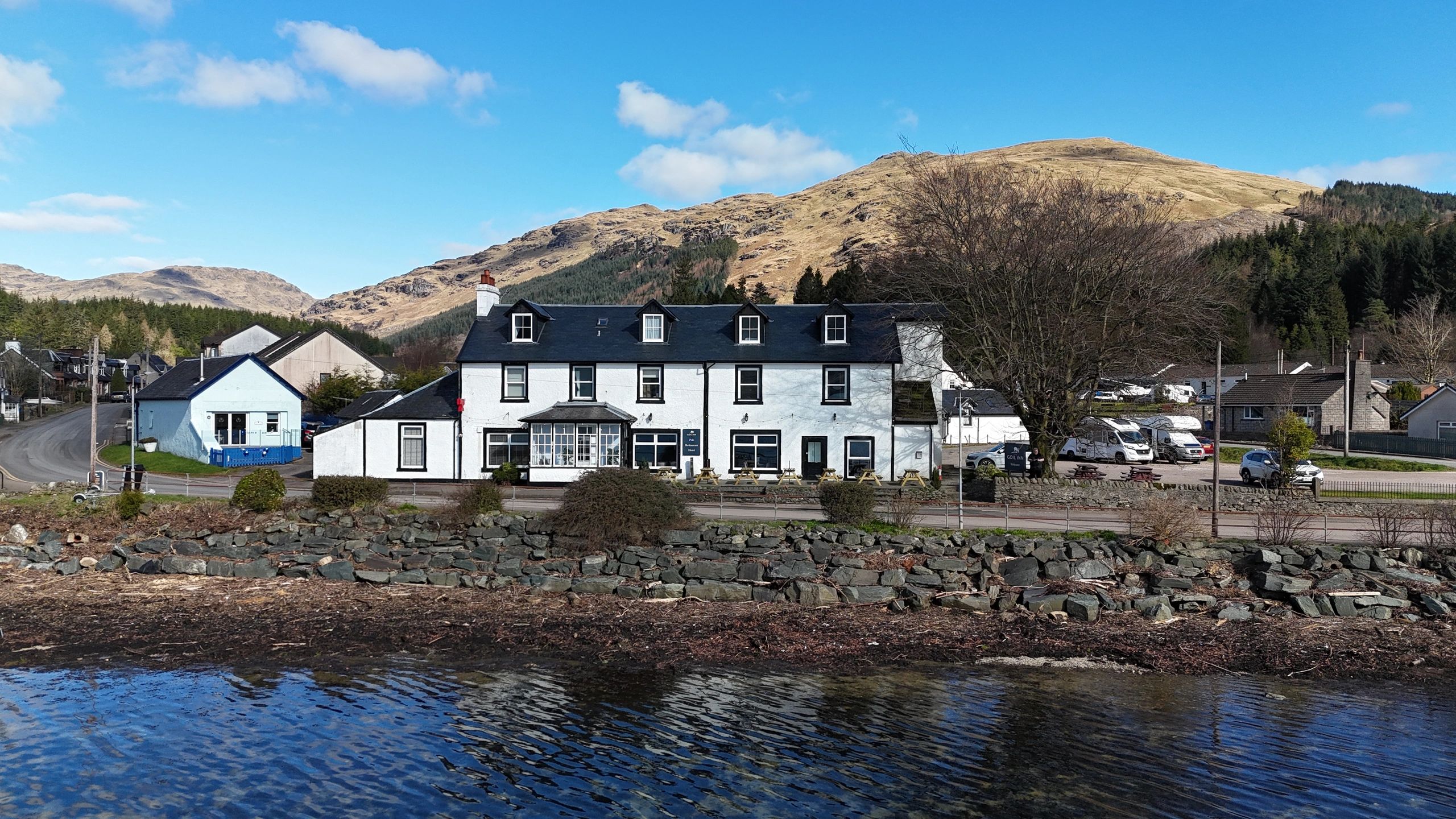 A white building by the waterfront with mountains in the background.