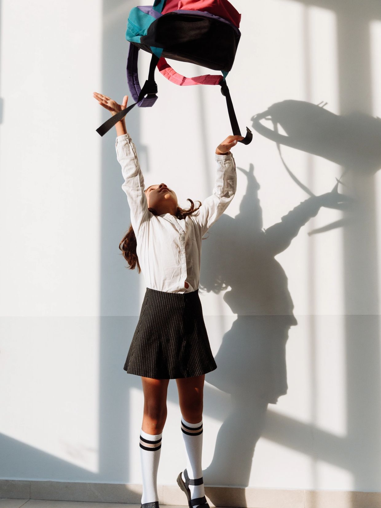 Young girl throwing the backpack up into the air