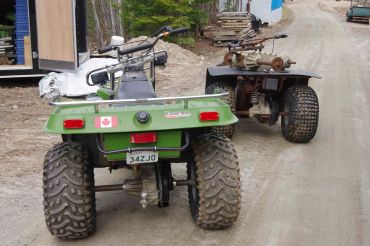 Two ATVs parked on a dirt road.