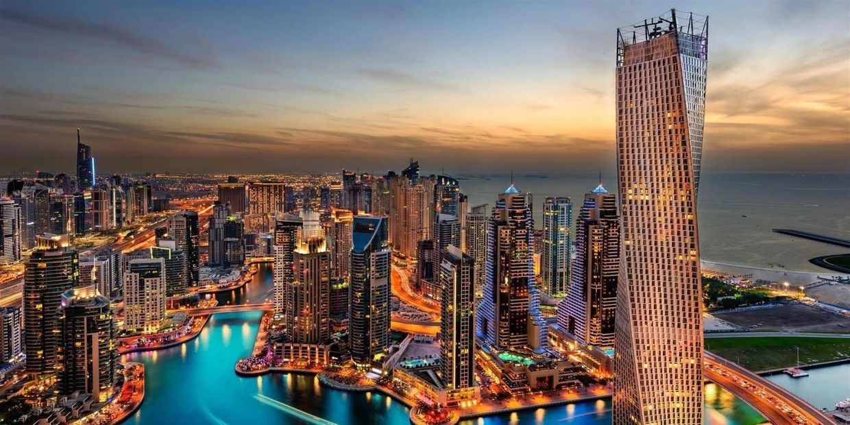 A stunning cityscape of Dubai Marina at sunset with illuminated skyscrapers and waterways.
