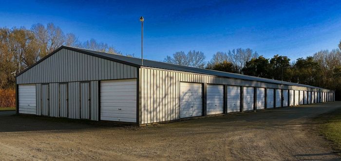 Long row of white garage doors on a metal building under a clear blue sky.