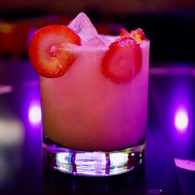 Pink cocktail with strawberries and ice.