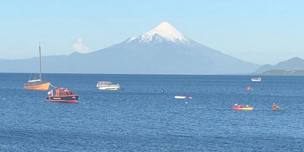 Foreground: water full of colourful boats, background: a large pointed mountain in the distance