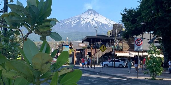 A street in Chile with a view of a mountain in the distance and leaves in the foreground.