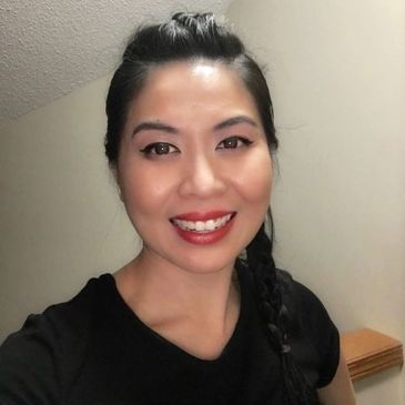 Smiling woman with braided hair and bright makeup.