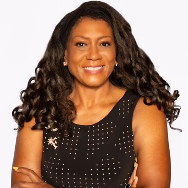 Confident woman with curly hair in a black studded dress, smiling warmly.