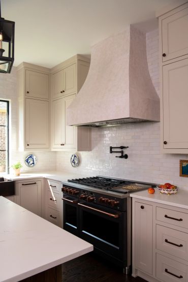 Elegant kitchen with black stove and beige cabinets.