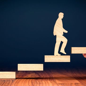 Wooden figure climbing wooden stairs symbolizing progress and growth.
