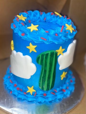 Colorful first birthday cake with stars, clouds, and blue frosting.
