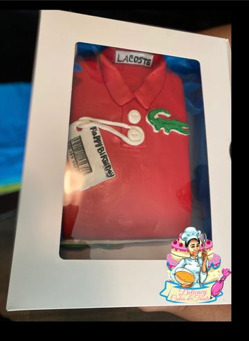 Red Lacoste polo shirt cake with detailed logo and buttons in a white box.