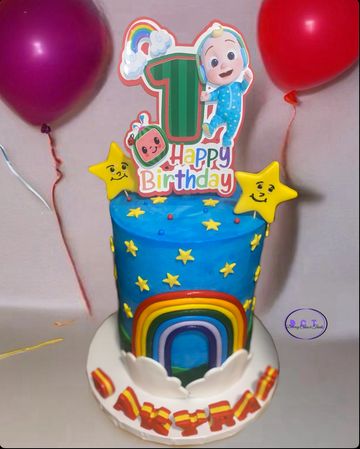 Colorful first birthday cake with stars, rainbow, and balloons.