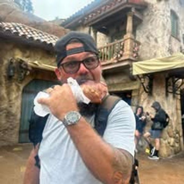 Man eating a turkey leg in a rustic outdoor setting.