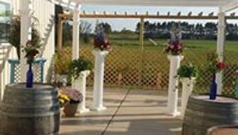 Outdoor wedding ceremony setup with floral decorations and wine barrels.