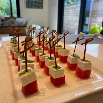 Watermelon and feta skewers with herb drizzle, served as a fresh summer appetizer on a white platter