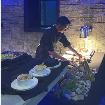 Chef preparing plated appetizers at a live carving station during a catered event.
