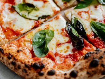 Neapolitan pizza with mozzarella, tomato sauce, and fresh basil leaves.

