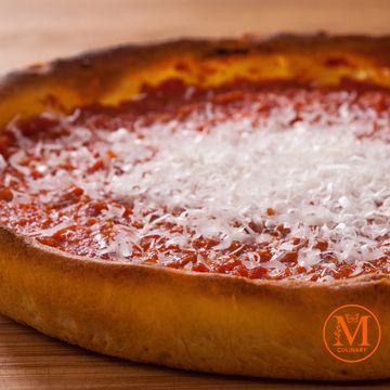 Close-up of a pizza crust topped with tomato sauce and grated cheese.