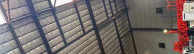 Interior view of a large industrial warehouse ceiling with metal beams and insulation.