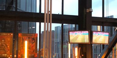 Bar interior with glowing lights and TVs showing a soccer match.