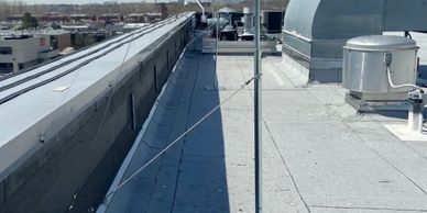A rooftop with HVAC equipment and a safety wire.