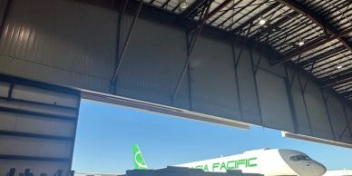 Cebu Pacific airplane parked inside a large hangar under a clear sky.