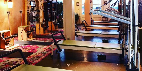 Interior of a Pilates studio with reformer machines and warm lighting.