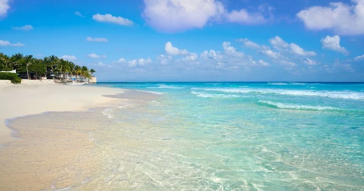 Playa tropical con arena blanca y mar azul claro.