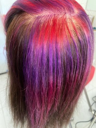 Hair dyed with vibrant red and purple colors.
