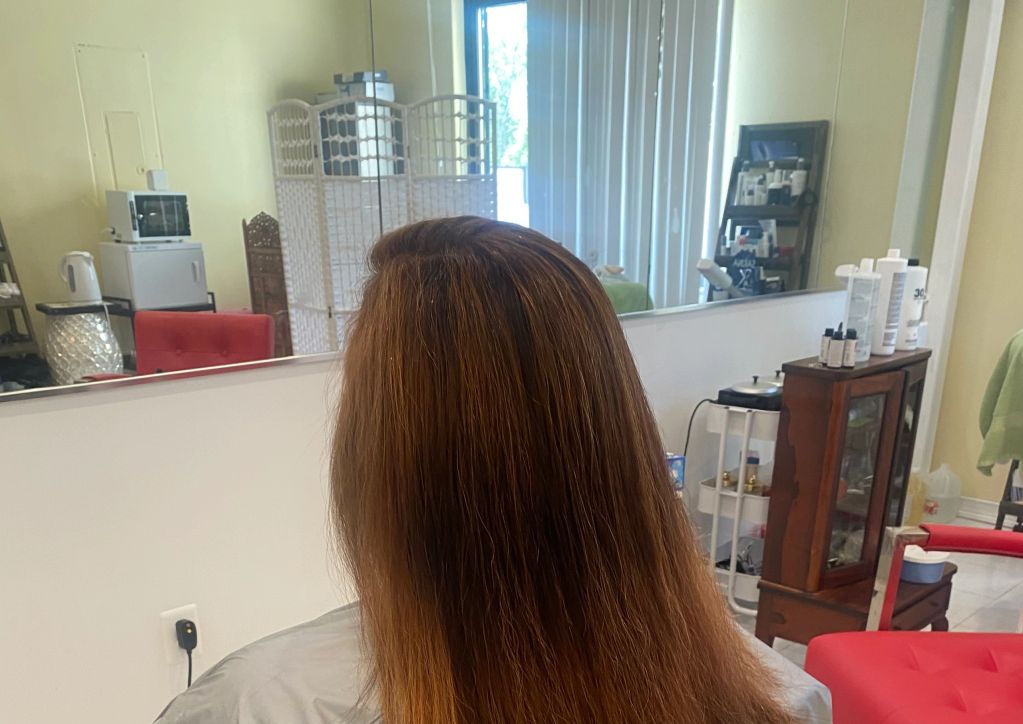 Person with long brown hair sitting in a salon chair.