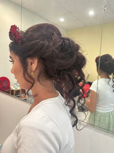 Elegant side profile of a woman with a curly updo hairstyle adorned with a red accessory.