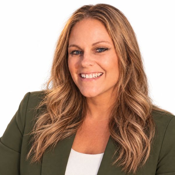 Smiling woman with wavy hair in a green jacket.