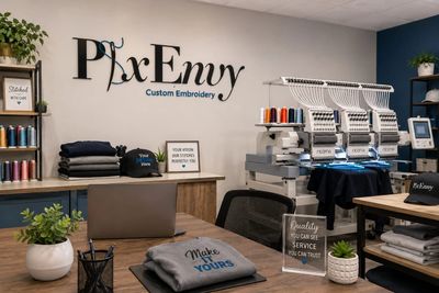 A neat embroidery workspace with machines, threads, and customized apparel.
