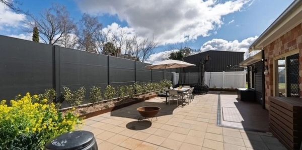 Spacious backyard patio with outdoor dining and umbrella under sunny sky.