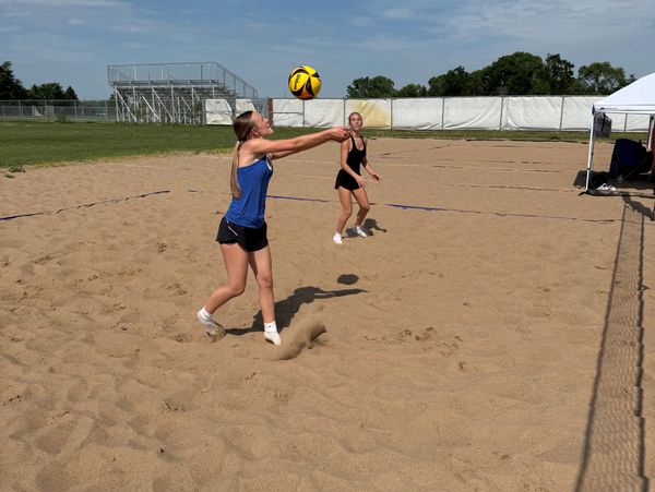 Two women playing beach volleyball on a sunny day.