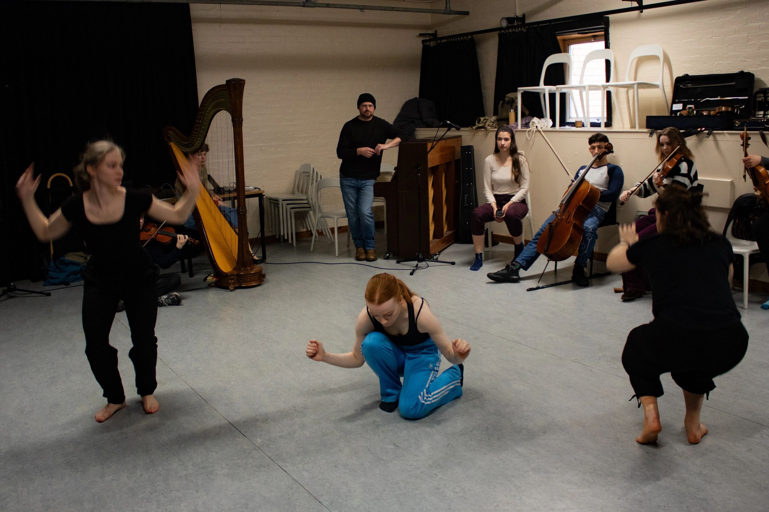 Group rehearsing with musicians and dancers in a studio.