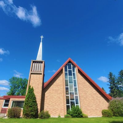 A church with a tall steeple and cross under a clear blue sky.