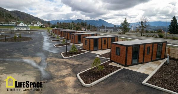Modern tiny homes arranged in a neat community with mountainous background.